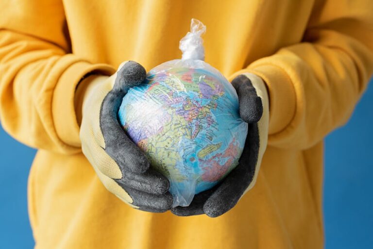 Close-up view of gloved hands holding a globe wrapped in plastic, symbolizing environmental issues.