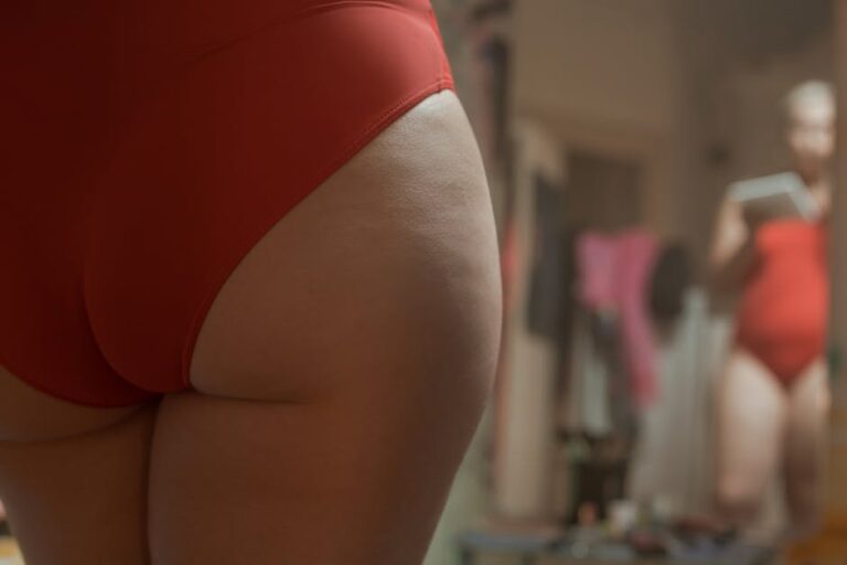 A close-up view of a person embracing body positivity in red swimwear, self-reflecting in a mirror.