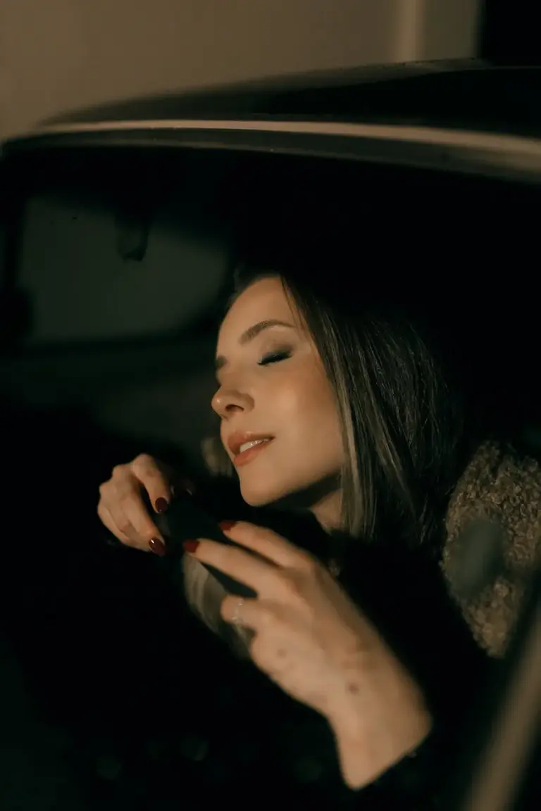 Woman with closed eyes in a car enjoying a serene moment at night.