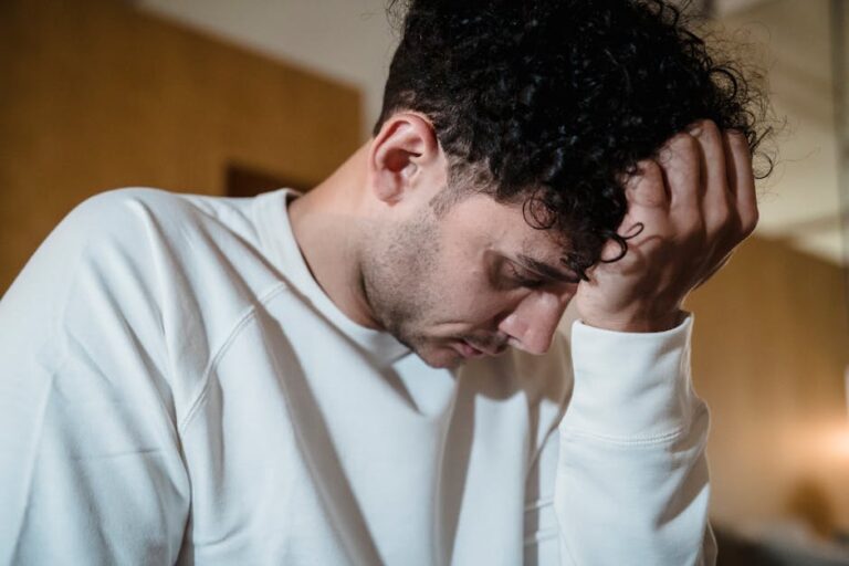 A man in a white sweater appears deep in thought, conveying emotion and introspection.