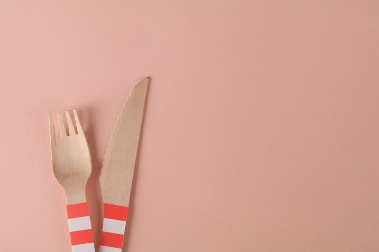 Eco-friendly wooden fork and knife set against a minimalist pink surface, perfect for sustainable lifestyle themes.