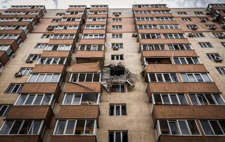 Low-angle view of a damaged apartment building in Kyiv, Ukraine with visible destruction.
