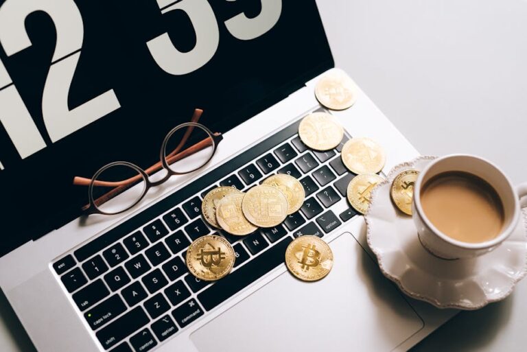 Laptop keyboard covered with Bitcoin coins and a coffee cup nearby, symbolizing cryptocurrency and work balance.