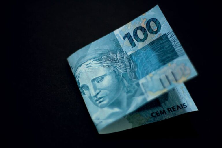 A Brazilian 100 real banknote displayed against a black backdrop, highlighting its design and color.